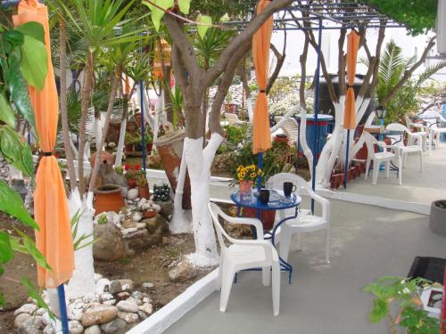 a patio with chairs and tables and umbrellas at Boussetil Rooms CapAnMat in Tinos Town