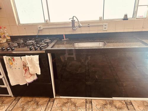 una cocina con fregadero y estufa horno superior en Casa Caragua, en Caraguatatuba