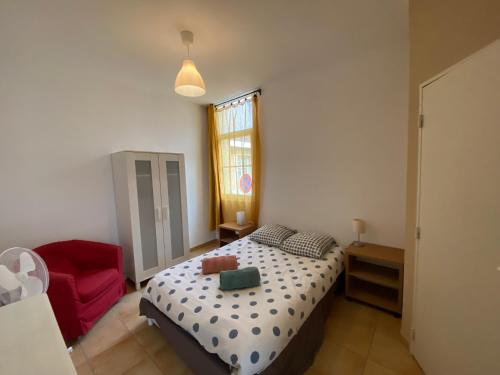 una camera da letto con un letto e una sedia rossa di Appartement familial centre et plage a Soulac-sur-Mer