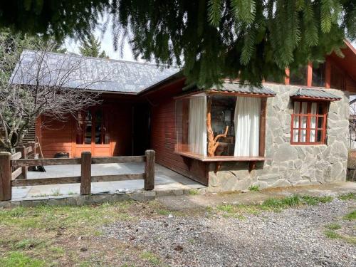 a house with a wooden fence in front of it at Cabaña Los Pinos in Malalcahuello
