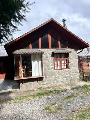 a small stone house with a cat sitting in a window at Cabaña Los Pinos in Malalcahuello