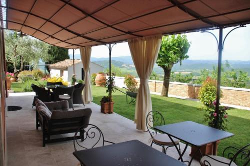 een patio met tafels en stoelen onder een grote parasol bij B&B Il Canto del Gallo in Casole dʼElsa