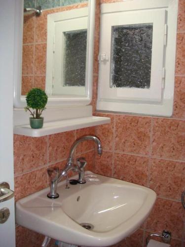 a bathroom with a sink and two windows at Boussetil Rooms CapAnMat in Tinos Town