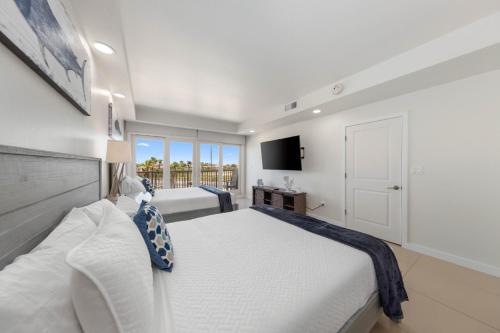 Un dormitorio blanco con una cama grande y un televisor. en Beachfront Luxury Renewed Condo, en South Padre Island