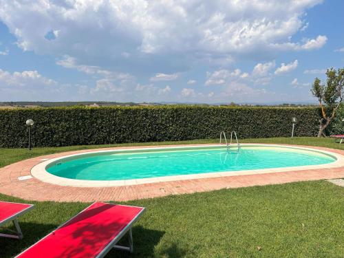 a swimming pool in a yard with two red chairs at Casale Fattoria Benaris With Private Pool - Marsiliana in Marsiliana