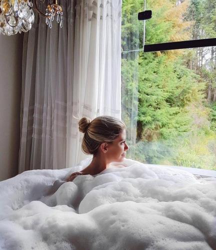 a woman laying in a bed in front of a window at Alma Hotel in Campos do Jordão