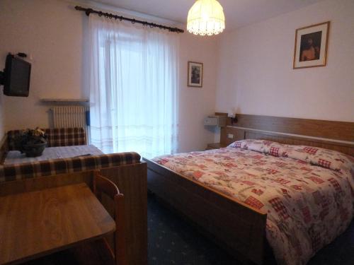 a bedroom with a bed and a tv and a window at Garnì Defrancesco in Campitello di Fassa