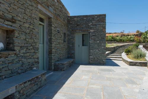 a stone building with a blue door and stairs at Xenonas Sifnos in Faros