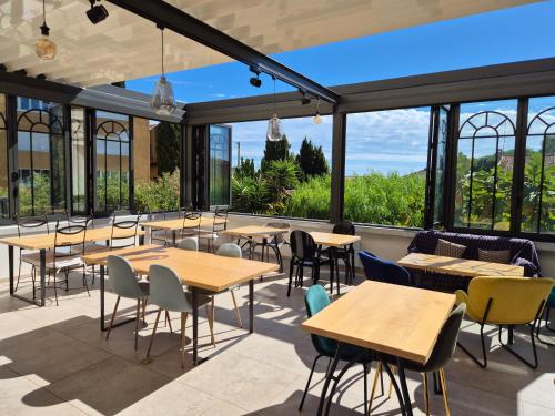 a restaurant with tables and chairs and large windows at Hôtel La Petite Bohème in Le Lavandou
