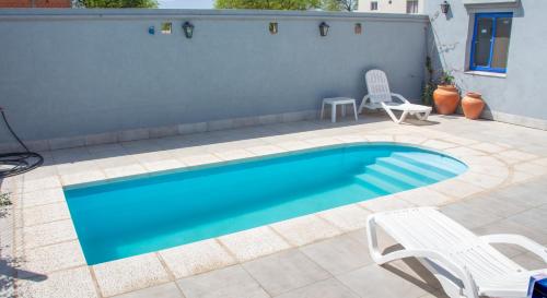 - une piscine avec 2 chaises et un banc dans l'établissement Departamentos La Justina, à Cafayate