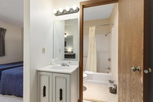 Un baño con lavabo, inodoro y espejo. en Pelican Lakes Motel, en Breezy Point
