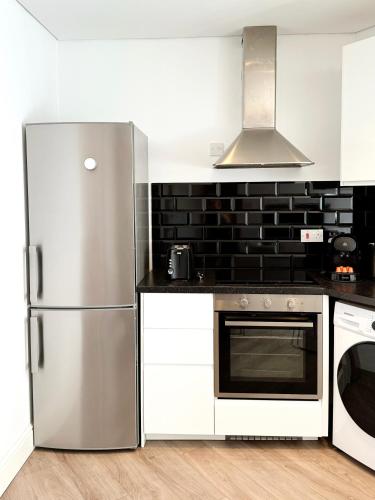 a kitchen with a stainless steel refrigerator and white cabinets at Modern City Centre Two Bedroom Windsor Apartment - Grand Central House in Gibraltar