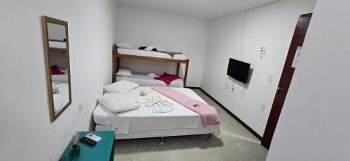 a small bedroom with two beds and a mirror at Pousada Pé Na Areia in Arraial do Cabo