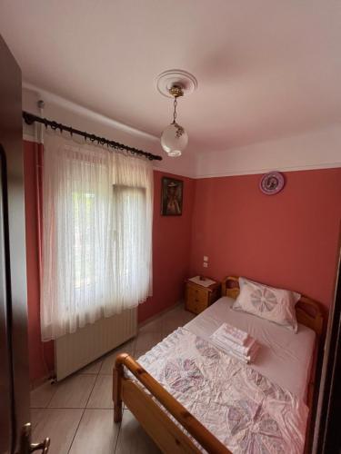 a bedroom with a bed with red walls and a window at Veronika house Under Meteora in Sarakína