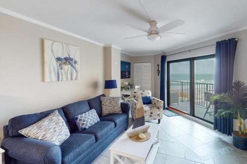 a living room with a blue couch and a balcony at Peer at the Pier in Daytona Beach Shores