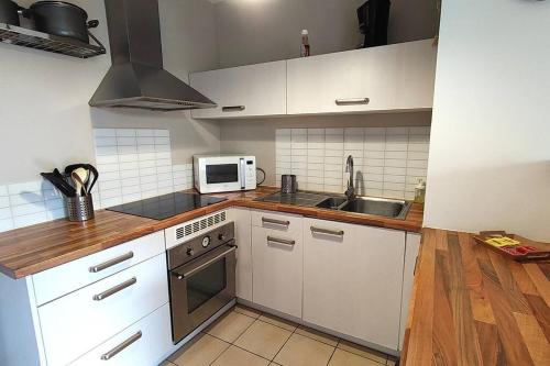 une cuisine avec des armoires blanches, un évier et un micro-ondes dans l'établissement Agréable T2 avec terrasse Proche gare, à Brétigny-sur-Orge