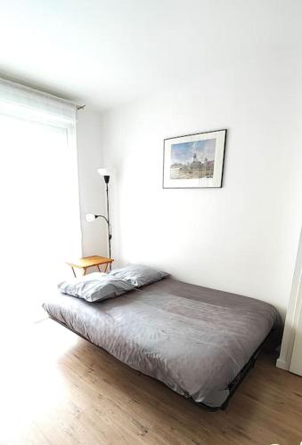 un lit dans une chambre blanche avec une fenêtre dans l'établissement Agréable T2 avec terrasse Proche gare, à Brétigny-sur-Orge