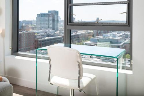 a glass table and a white chair in front of a window at Upscale 1BR near MIT Harvard with Parking in Cambridge