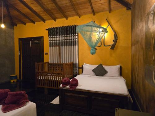 a bedroom with a bed and a lamp and a crib at Ceylon Resort Wilpattu in Wilpattu