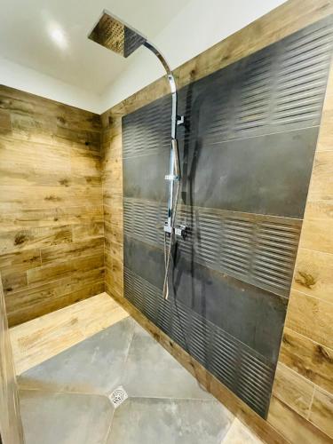 une douche dans une salle de bain avec un mur en bois dans l'établissement Maison plain-pied, à Chamadelle