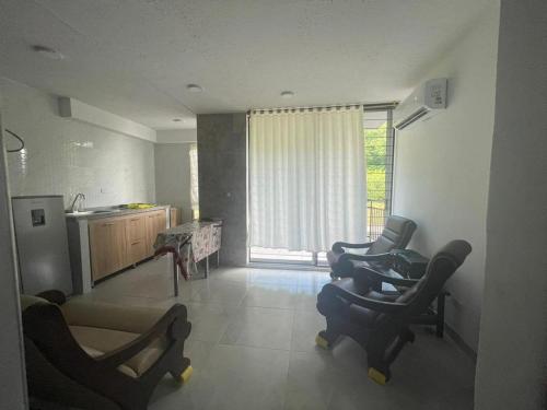 a living room with chairs and a kitchen with a window at Condominio Bahía Solero Girardot in Ricaurte