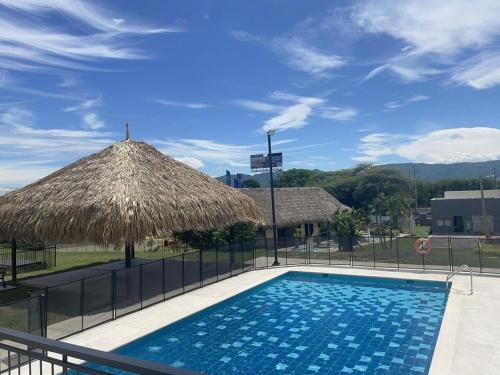 a swimming pool with a straw umbrella and a swimming pool at Condominio Bahía Solero Girardot in Ricaurte