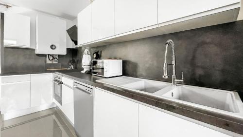une cuisine avec des armoires blanches et un évier dans l'établissement Homey Luxury - Proche du centre-ville, des transports, de Genève, à Annemasse