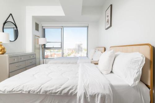 a white bedroom with a large white bed with a window at Central Serene Condo King Bed by MIT Harvard GYM in Cambridge