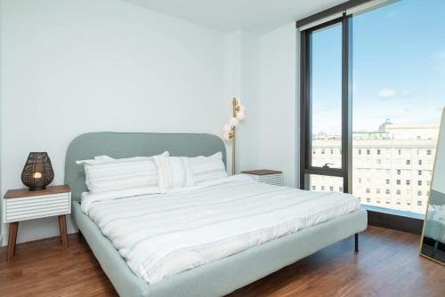 a white bed in a room with a large window at Back-Bay 2BR Penthouse w Roof top and GYM in Boston