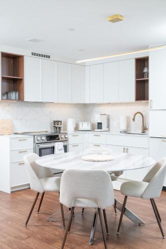 a kitchen with white cabinets and a table and chairs at Back-Bay 2BR Penthouse w Roof top and GYM in Boston