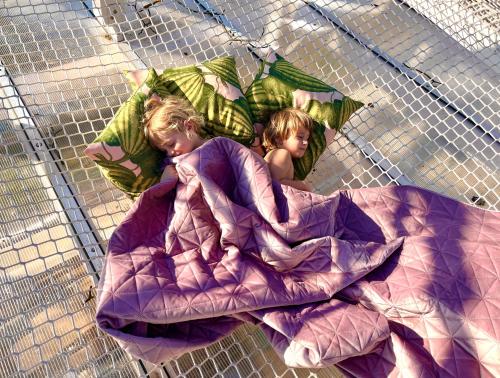 two little girls laying on a blanket on a bed at Bohemian ECO lodge in Kisapáti