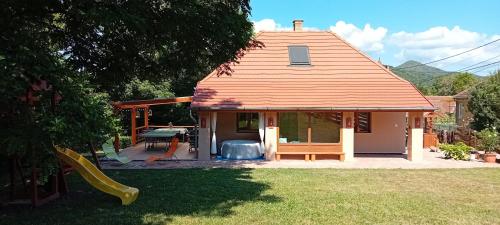 a small house with a patio and a table at Hollós-patak Vendégház in Komlóska