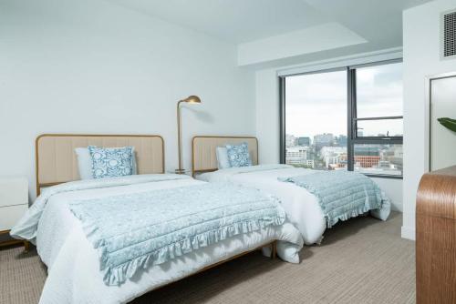 two beds in a bedroom with a large window at Central Serene Penthouse w King bed GYM Parking in Cambridge