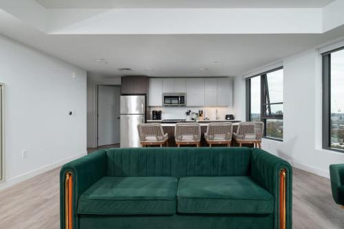a living room with a green couch and a kitchen at Central Serene Penthouse w King bed GYM Parking in Cambridge