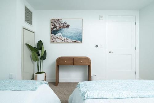 a white bedroom with two beds and a table at Central Square Penthouse near MIT Harvard Wi-Fi & GYM in Cambridge