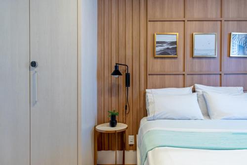 a bedroom with a bed and a table with a lamp at PALMAS EXPERIENCE - APARTAMENTO CONTEMPORÂNEO, vista serra, na quadra do shopping in Palmas