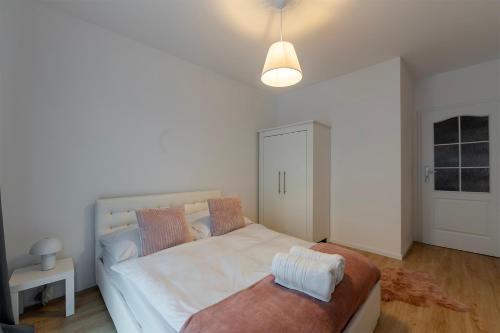 a bedroom with a large white bed and a bench at Rosa Apart Janów z miejscem parkingowym in Łódź