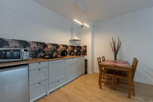 a kitchen with a table and a microwave at Rosa Apart Janów z miejscem parkingowym in Łódź