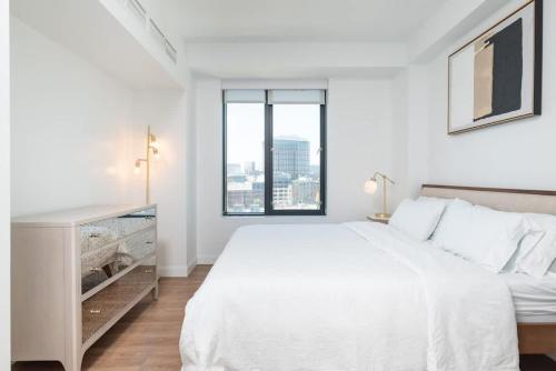 a white bedroom with a white bed and a window at Luxury Apartment w King Bed Shared Pool & Rooftop in Cambridge
