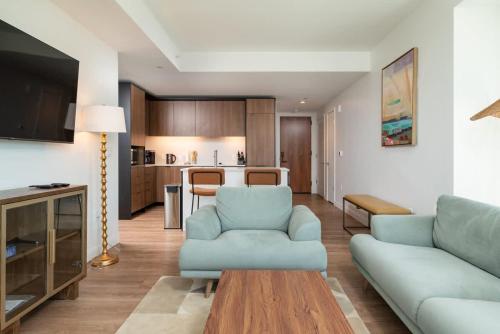 a living room with a blue couch and a kitchen at Luxury Apartment w King Bed Shared Pool & Rooftop in Cambridge