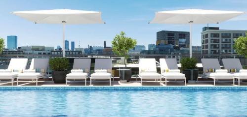 a group of lounge chairs and umbrellas next to a pool at Luxury Apartment w King Bed Shared Pool & Rooftop in Cambridge