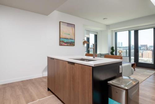 a kitchen with a sink and a living room at Luxury Apartment w King Bed Shared Pool & Rooftop in Cambridge