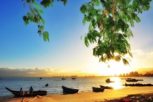 a group of boats on the beach at sunset at Apartamento Estúdio em Caraguatatuba com Garagem in Caraguatatuba