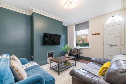 a living room with blue couches and a fireplace at Spacious Two Bed House in Headingley in Headingley