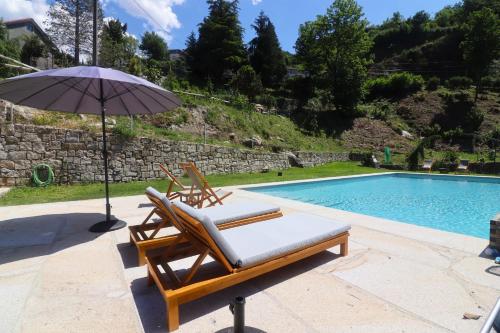 two lounge chairs and an umbrella next to a swimming pool at Quinta das Varcandas Gerês - Apartamento 2 by Gerês Casas in Geres