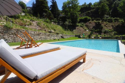 a pool with two lounge chairs and an umbrella at Quinta das Varcandas Gerês - Apartamento 2 by Gerês Casas in Geres