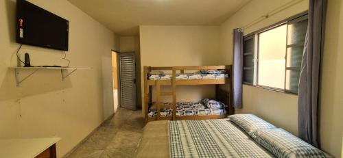 a small room with a bed and a tv and a window at Kit GT in São Carlos