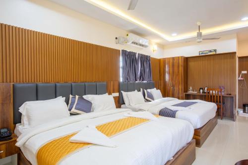 two beds in a hotel room with white sheets at Sruthi Residency in Rāmeswaram