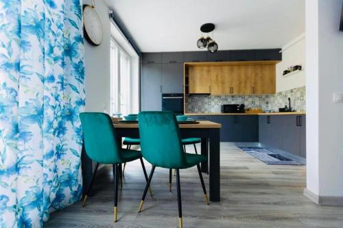 a kitchen with a table and four green chairs at Dominic Junior Apartment Sighisoara in Sighişoara