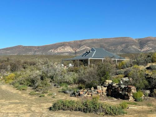 a house in the desert with mountains in the background at Paardefontein Karoo Stay in Laingsburg
